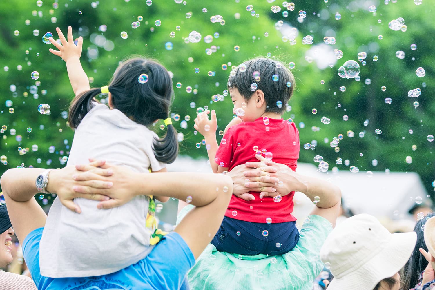 緑の木々を背景にシャボン玉の中で遊ぶ子どもたち、イメージ